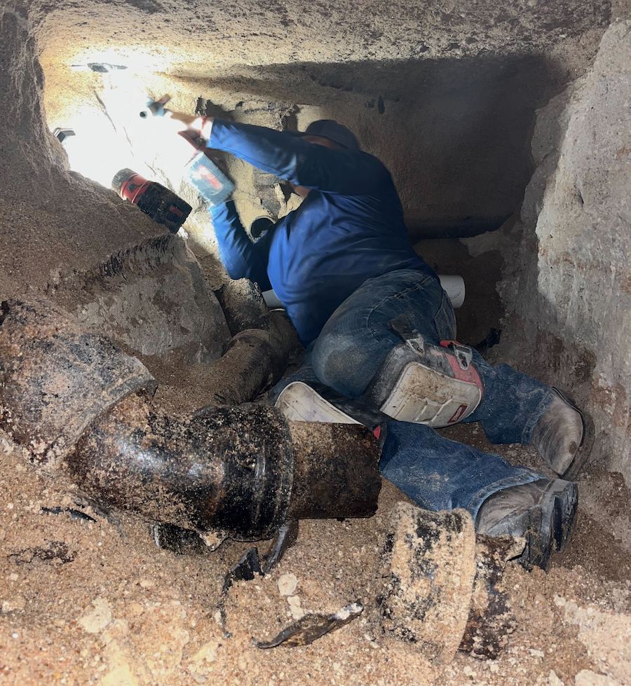 plumber replacing sewage pipes in underground tunneling.